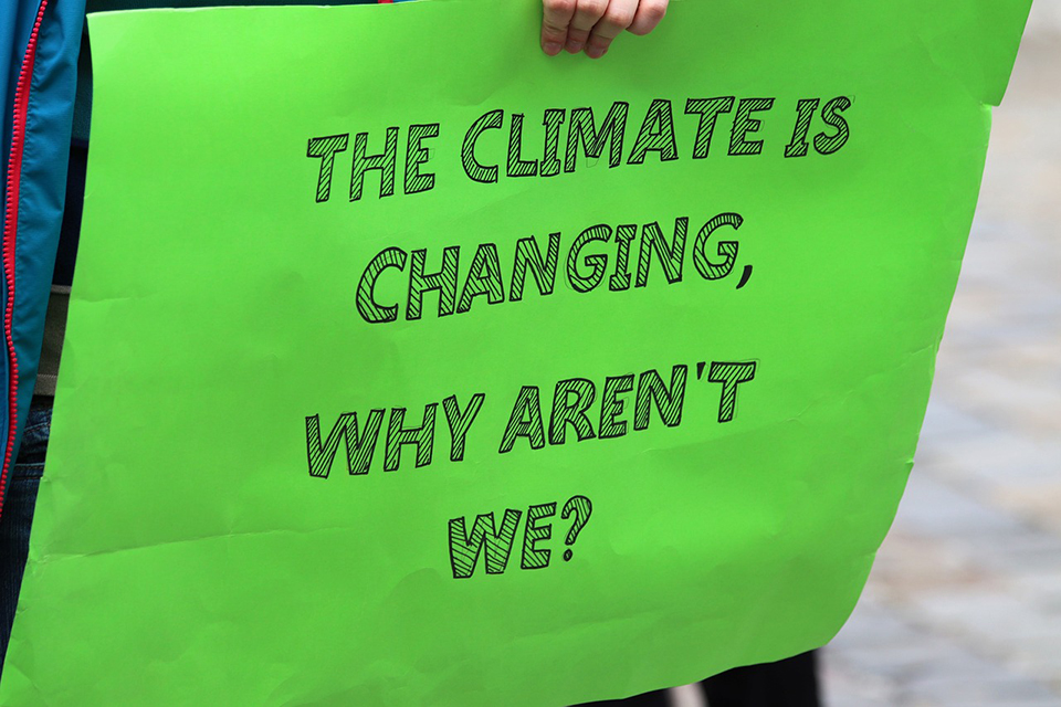 Photo for blog post, a green sign with words The Climte is Changing, Why aren't We