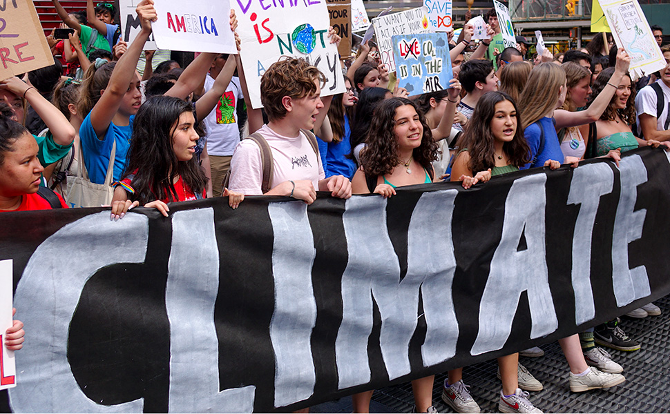 Young people chanting while holding a banner with the word Climate at a climate change protest