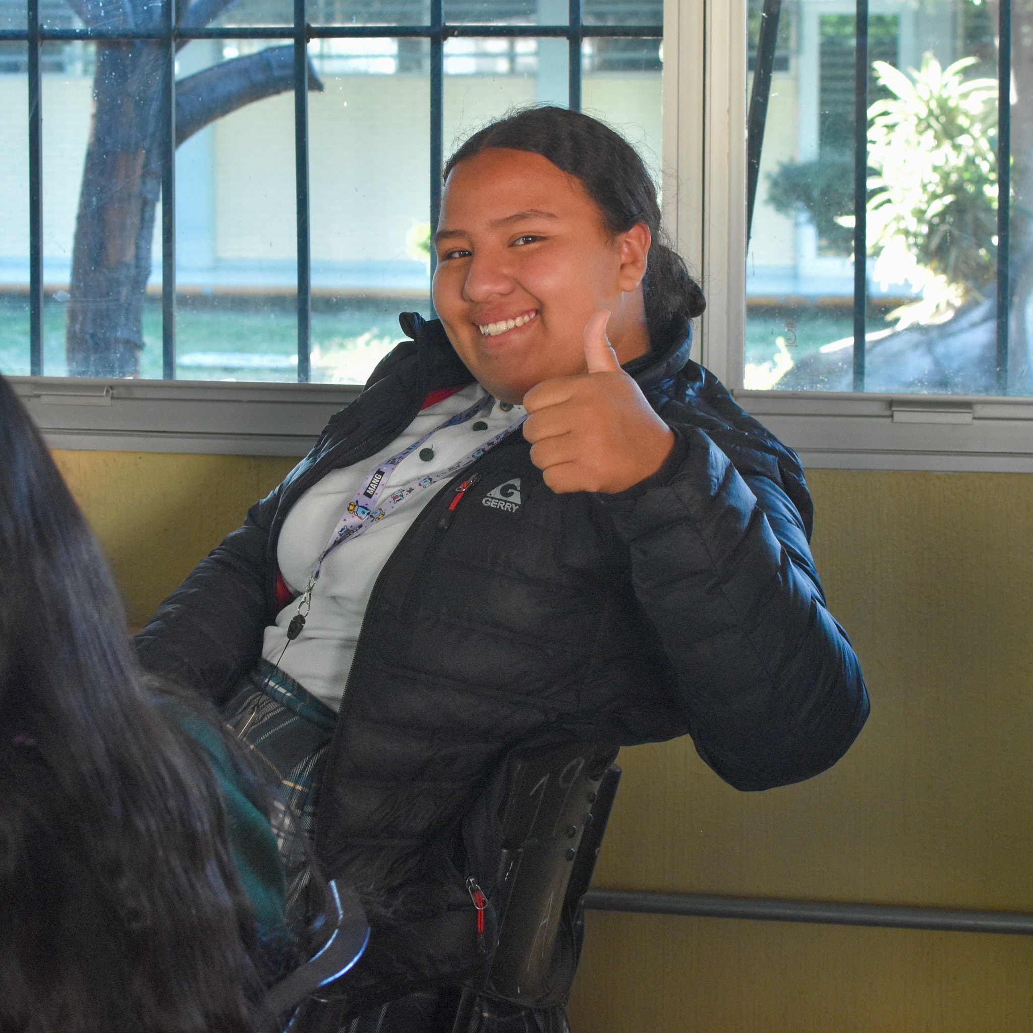 A student sitting at a desk and giving a thumbs up.